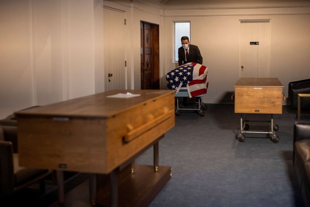 PHOTO: In this March 3, 2021, file photo, funeral coordinator Eddie Martinez moves a soldier's casket at the Hollywood Forever cemetery as it struggles to keep up with demand during the outbreak of COVID019 in Los Angeles.