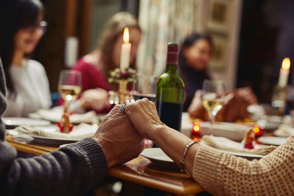 PHOTO: Closeup shot of people holding hands before having a meal together