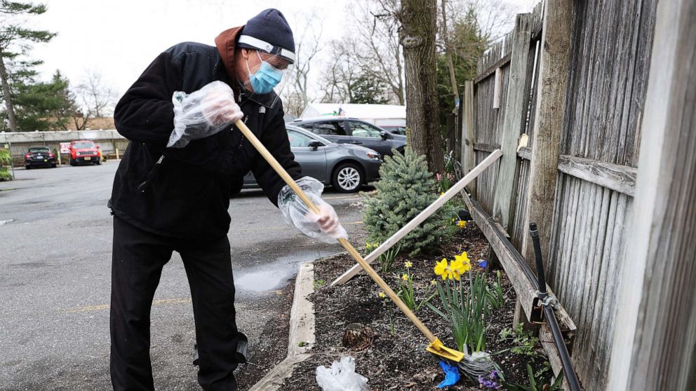PHOTO: Pat's Farms grocery store worker John Fedash cleans up the used gloves left in the parking lot and shopping carts in Merrick, N.Y., March 31, 2020.
