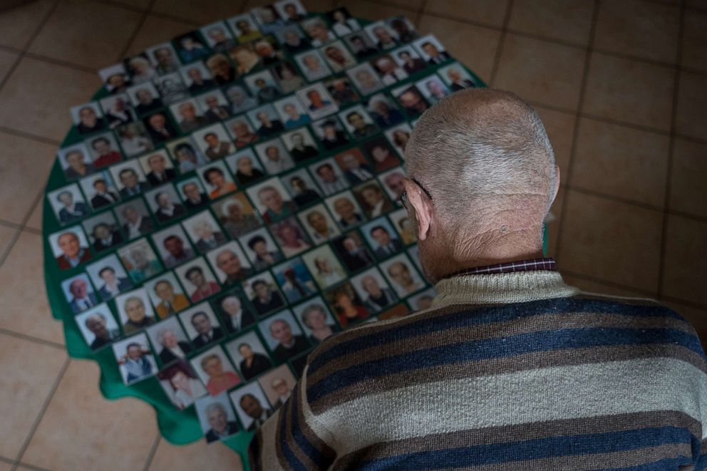 PHOTO: Gino Verani, 87, observes a collection of "santino" cards, a traditional laminated card with a picture of a deceased person on the front and a prayer on the back in his home in San Fiorano, Italy, March 14, 2020.