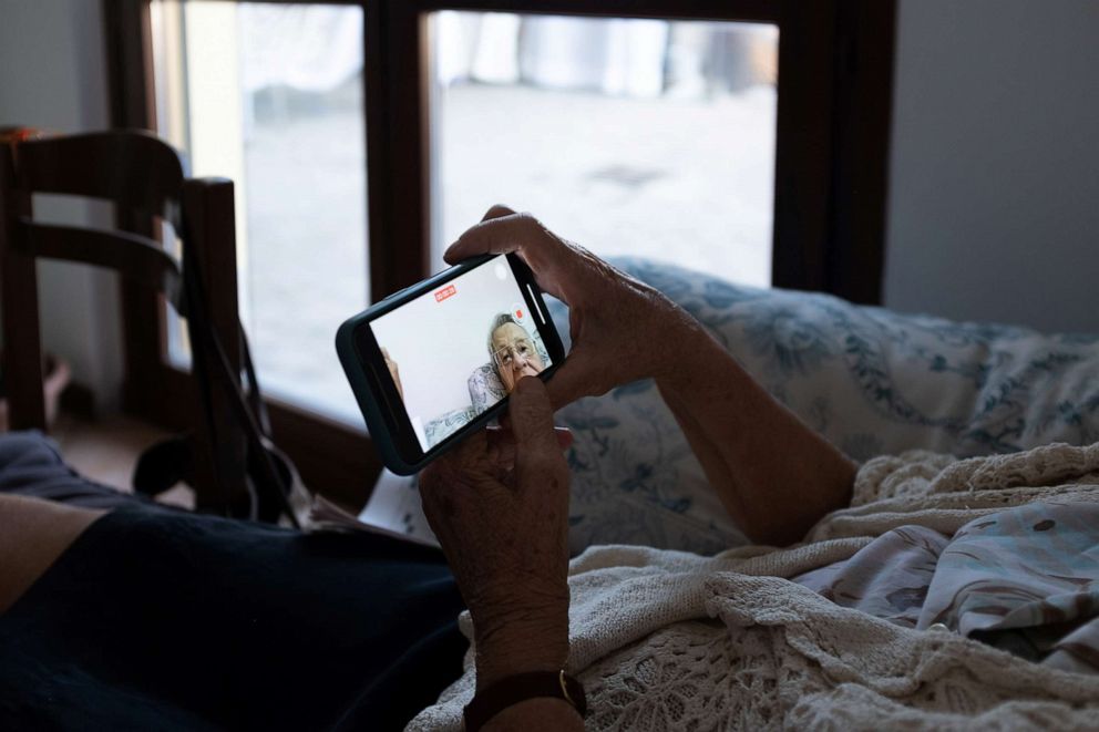 PHOTO: Ines Prandini records a video on a mobile phone, to be shown to her husband, Gino Verani, who is in care facility, during the coronavirus disease (COVID-19) outbreak, in San Fiorano, Italy, Sept. 3, 2020.