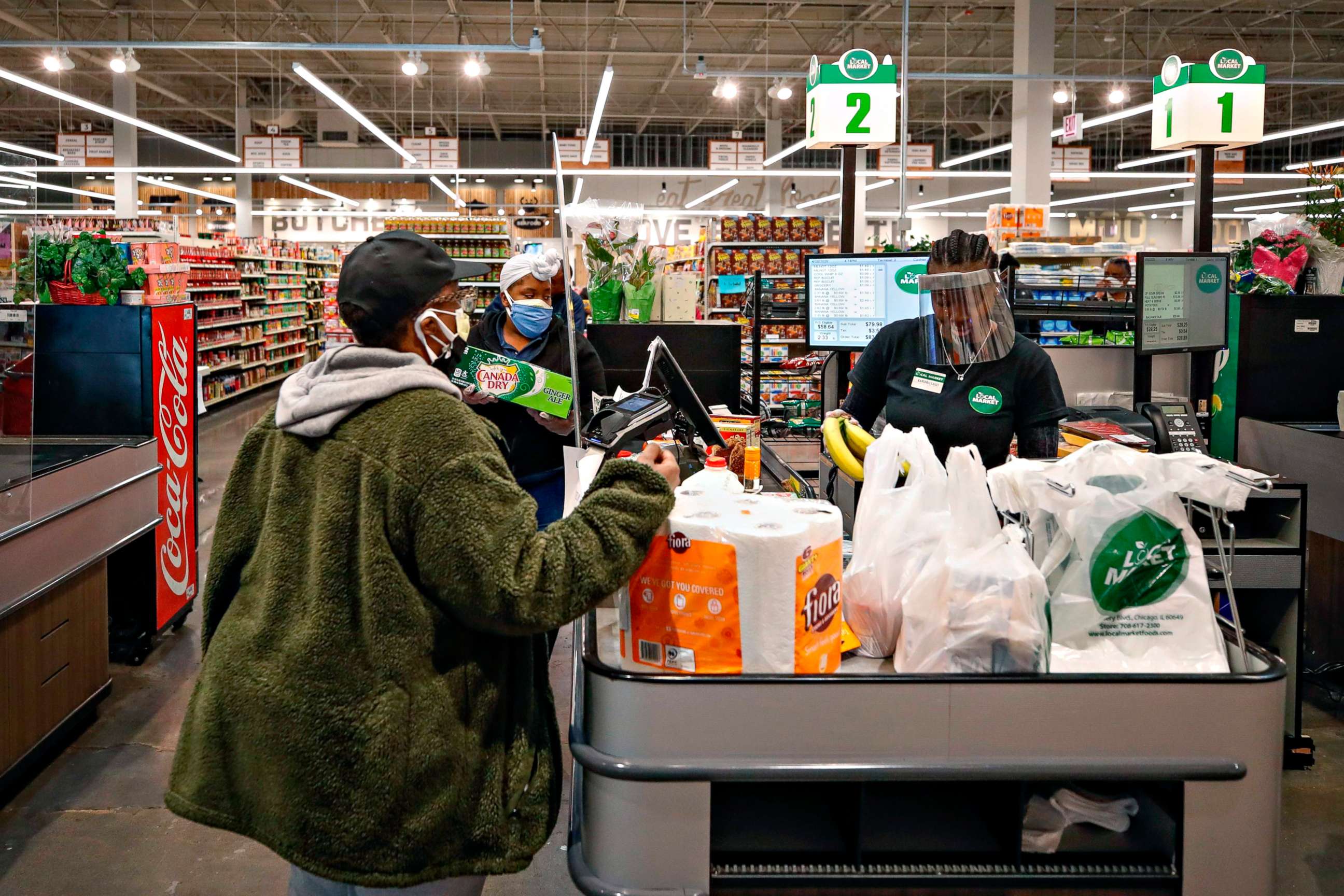PHOTO: A cashier wearing a face shield bags groceries for a customer at the Local Market Foods store in Chicago, April, 8, 2020.