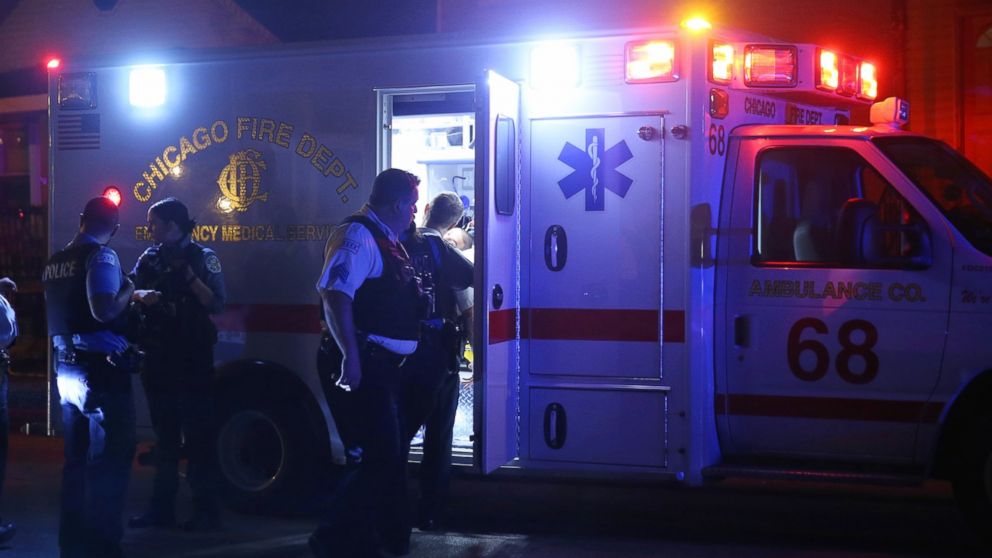 Police officers listen to a woman as paramedics tend to a man in an ambulance, Oct. 2, 2016, in Chicago, Ill.