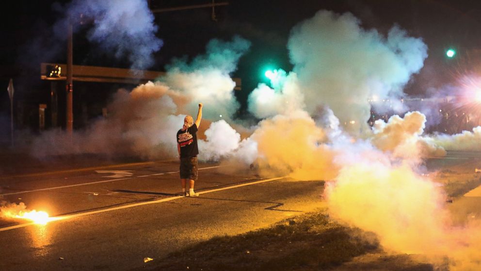 PHOTO: A demonstrator, protesting the shooting death of teenager Michael Brown, stands his ground as police fire tear gas on August 13, 2014 in Ferguson, Missouri. 