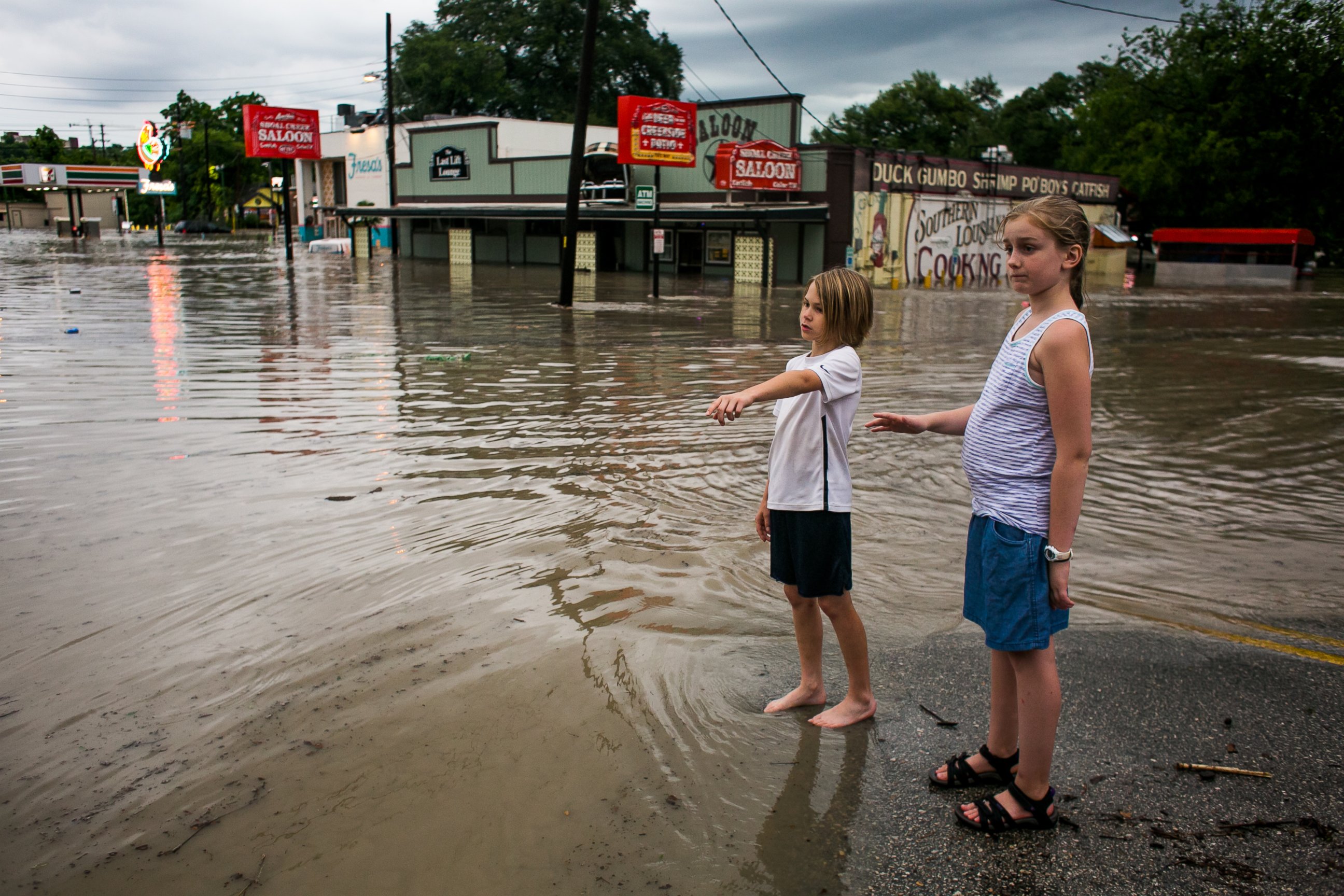 PHOTO: Murphy Canning and Annika Rolston watch as a street remains underwater from days of heavy rain on May 25, 2015 in Austin, Texas.