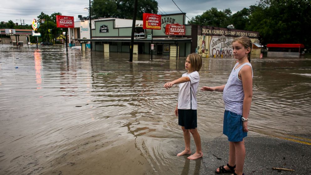 Murphy Canning and Annika Rolston watch as a street remains underwater from days of heavy rain on May 25, 2015 in Austin, Texas.