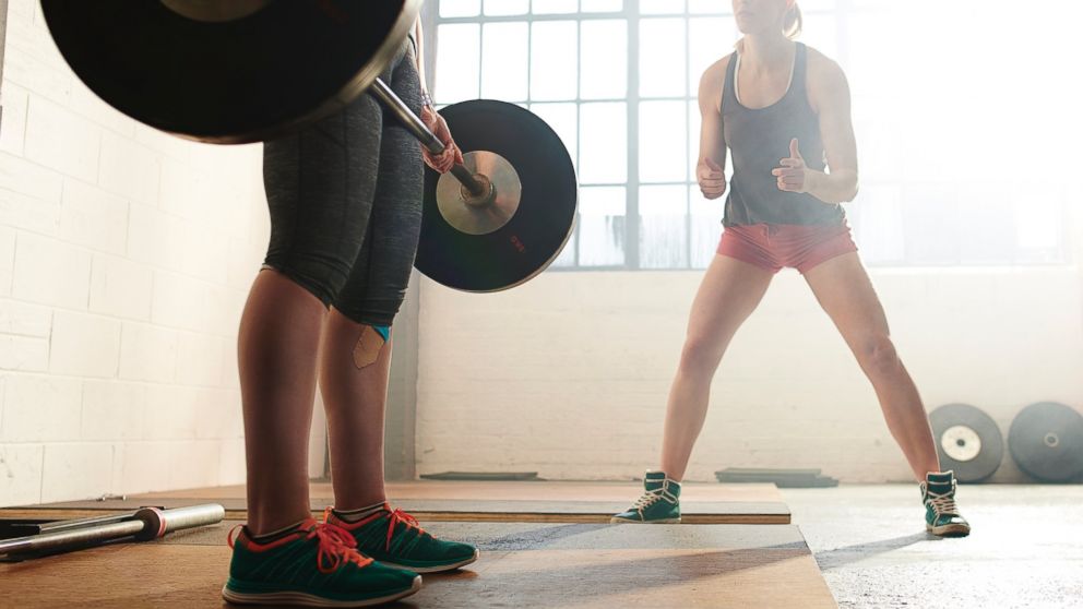 A woman lifts weights with a trainer in an undated stock photo.
