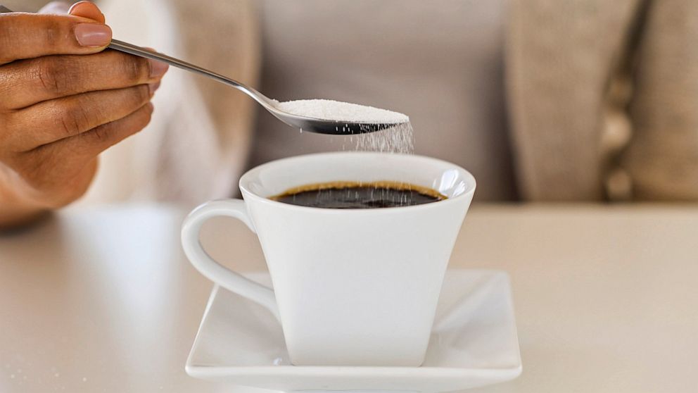 PHOTO: Woman spooning sweetener into coffee