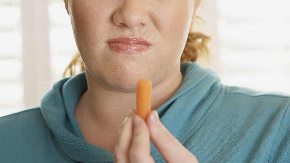 A woman makes a face while holding a carrot in an undated stock photo.