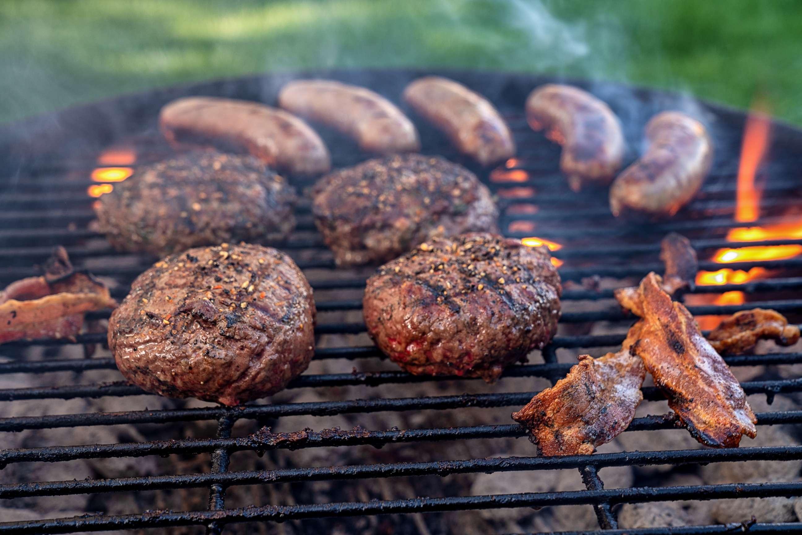 PHOTO: Cheeseburgers and Brats on a Fiery Charcoal Grill with Flames