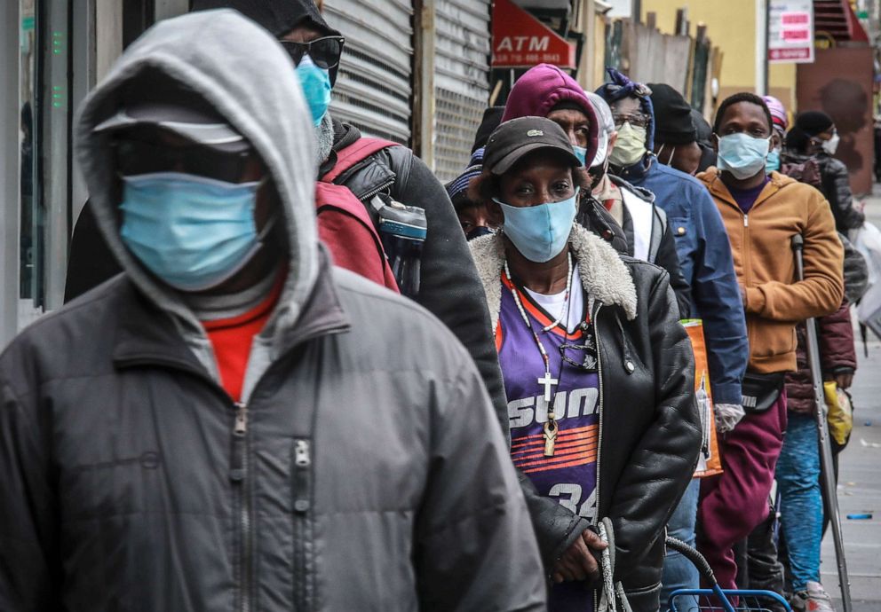 PHOTO: People wait for a distribution of masks and food from the Rev. Al Sharpton in the Harlem neighborhood of New York, April 18, 2020, after a new state mandate was issued requiring residents to wear face coverings in public due to COVID-19.