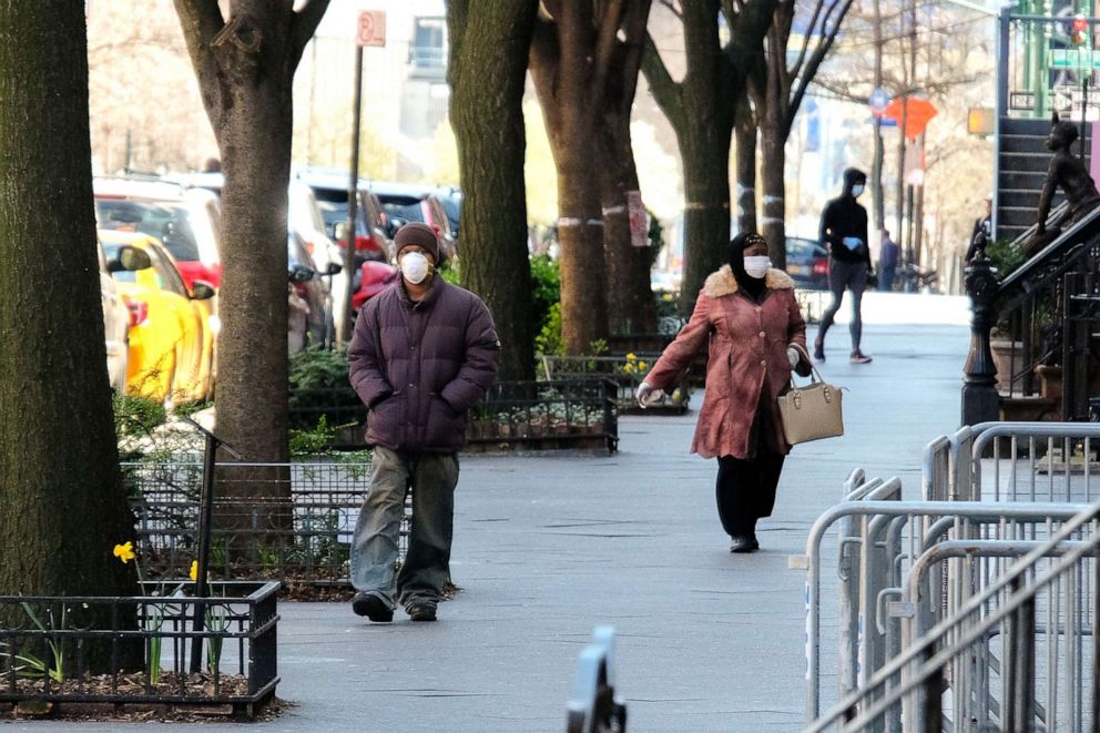 PHOTO: People wearing protective masks are seen walking in the Harlem neighborhood of Manhattan on April 2, 2020, in New York, as the coronavirus continues to spread across the United States.