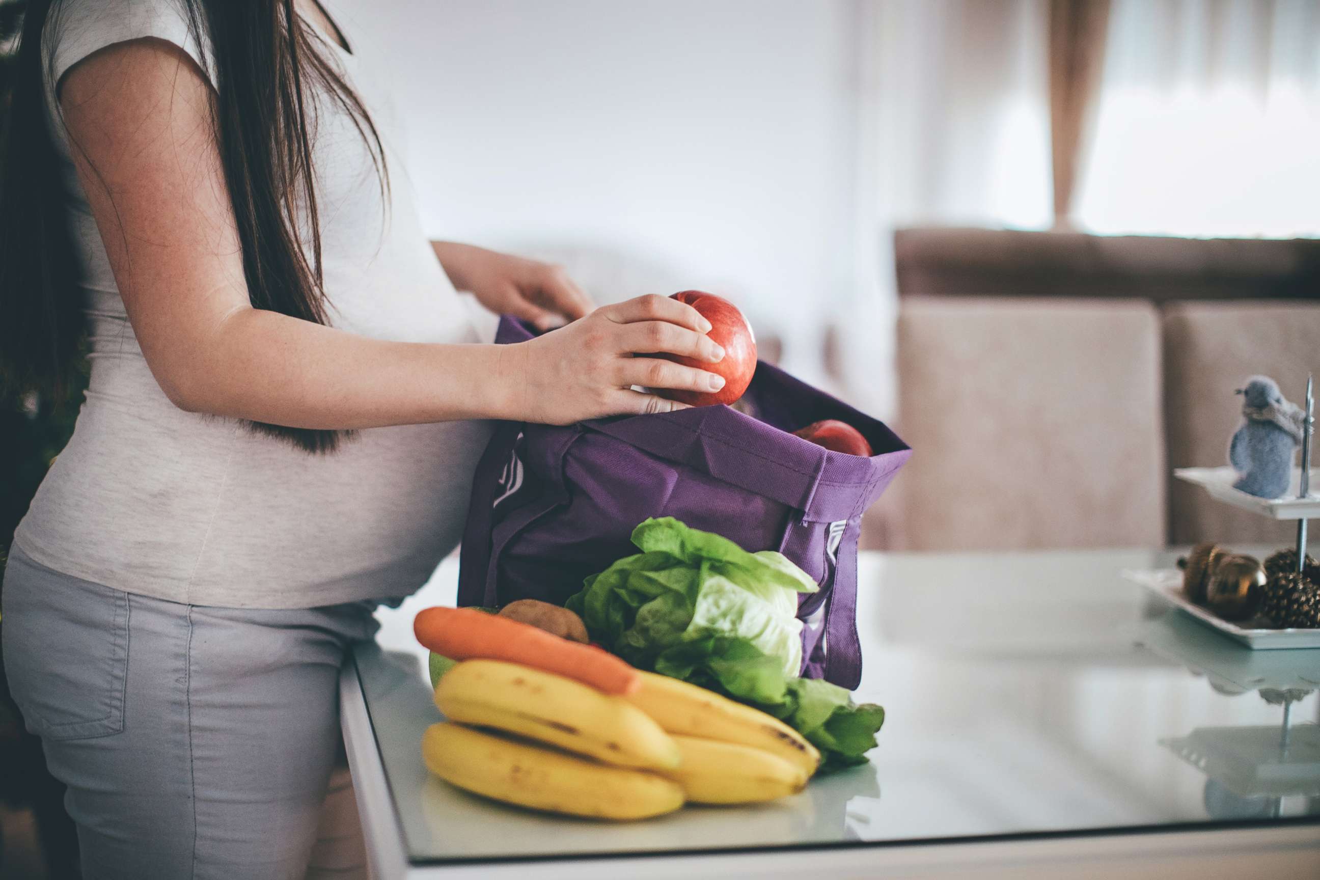 PHOTO: A pregnant woman removes fruit and vegetables from her shopping bag in an undated stock photo.