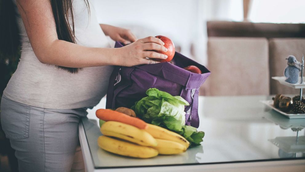 PHOTO: A pregnant woman removes fruit and vegetables from her shopping bag in an undated stock photo.