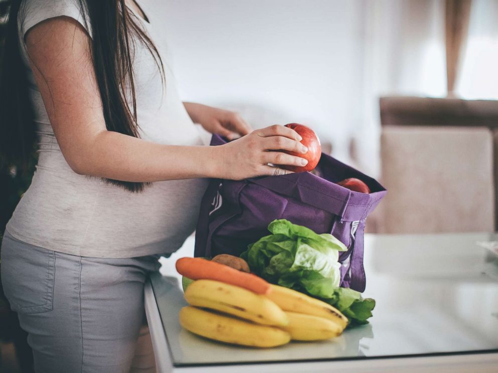 PHOTO: A pregnant woman removes fruit and vegetables from her shopping bag in an undated stock photo.