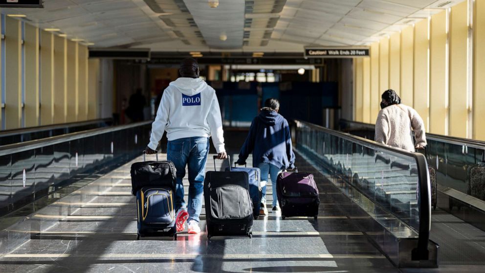PHOTO: Travelers carry luggage as they arrive at Ronald Reagan Washington National Airport in Arlington, Va., Nov. 23, 2021.