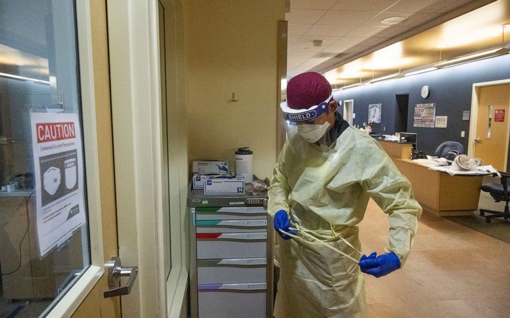 PHOTO: In this April 14, 2022, file photo, a nurse assistant puts on protective gear to go into a COVID-19 patient room at Providence St. Joseph Hospital in Orange, Calif.