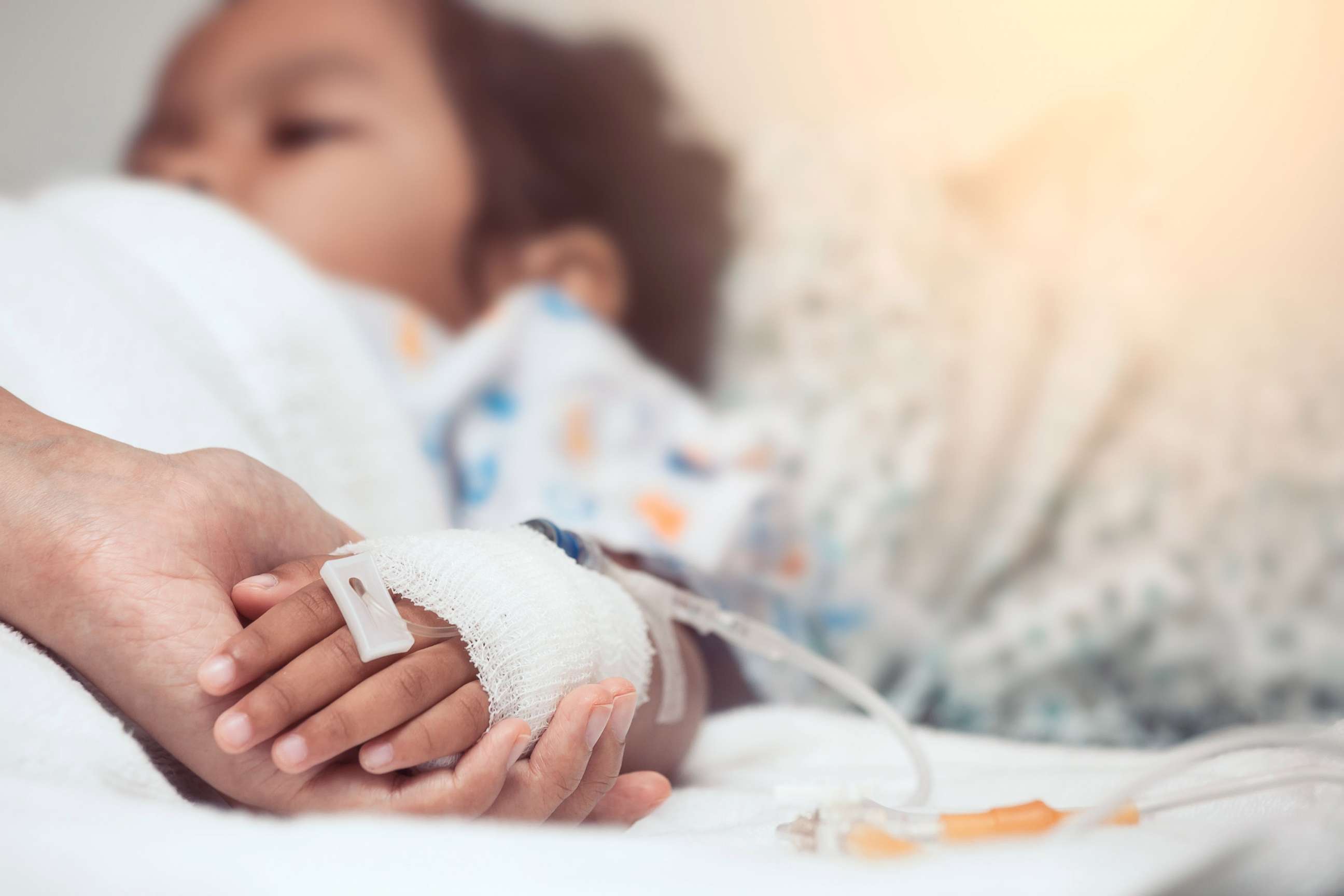 PHOTO: A mother holds her child's hand while she is hospitalized, in a stock image.