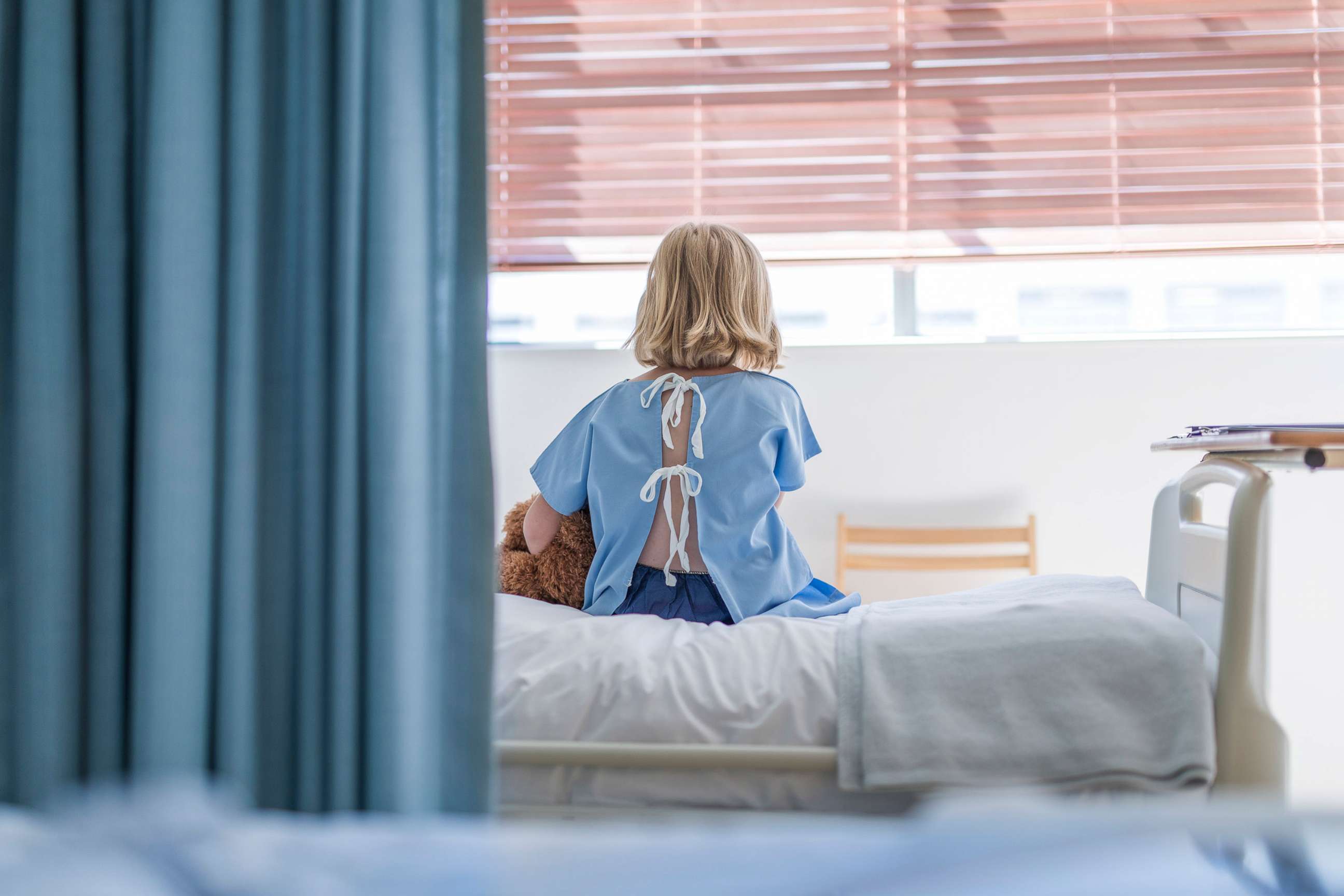 PHOTO: A child sits on bed while hospitalized, in a stock image.