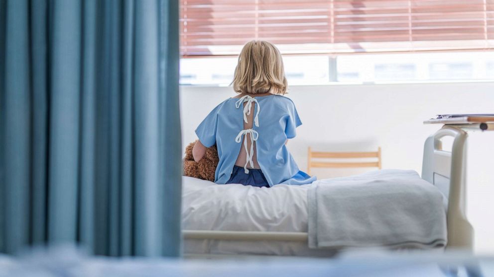 PHOTO: A child sits on bed while hospitalized, in a stock image.