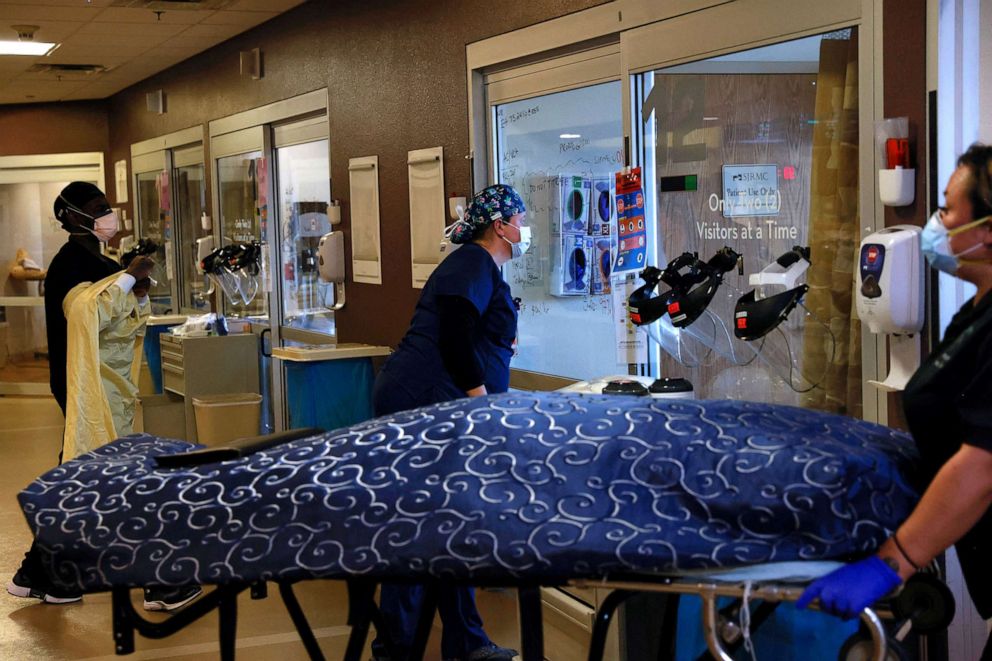 PHOTO: In this Dec. 10, 2021, file photo, a nurse looks in the isolation room of a COVID-19 patient as the body of a deceased COVID-19 patient leaves the intensive care unit at San Juan Regional Medical Center in Farmington, N.M.


