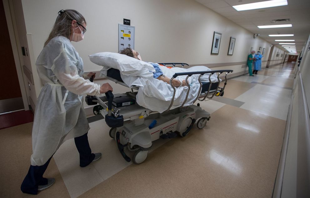 PHOTO: Maddie Dalby, a transporter at Gulf Coast Medical Center, returns a patient to his designated room after visiting with his doctors in Fort Myers, Fla., April 29, 2020.