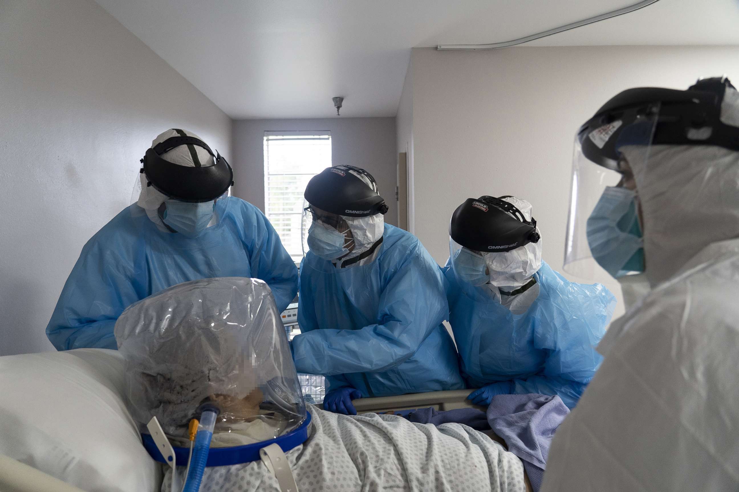 PHOTO: In this July 28, 2020, file photo, members of the medical staff treat a patient who is wearing a helmet-based ventilator in the COVID-19 intensive care unit at the United Memorial Medical Center in Houston.
