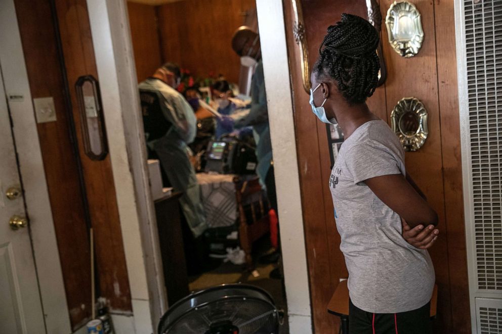 PHOTO: A girl watches as medics treat her grandmother suffering from possible COVID-19, Aug. 12, 2020, in Houston, Texas.