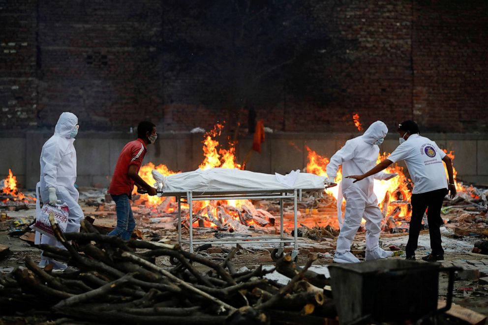 PHOTO: Relatives and health workers carry a body of a COVID-19 victim during a cremation at a crematorium in New Delhi, May 9, 2020.