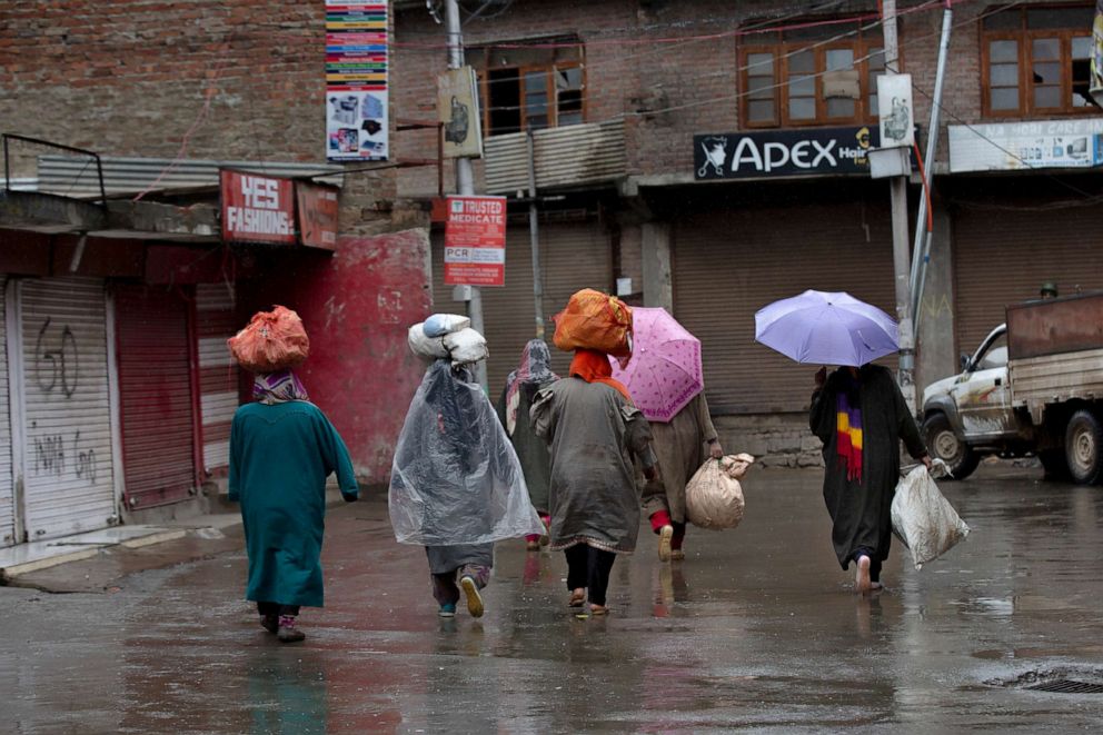 PHOTO: A group of Kashmiri women walk back home after selling vegetables during a lockdown in Srinagar Indian controlled Kashmir, March 27, 2020. 