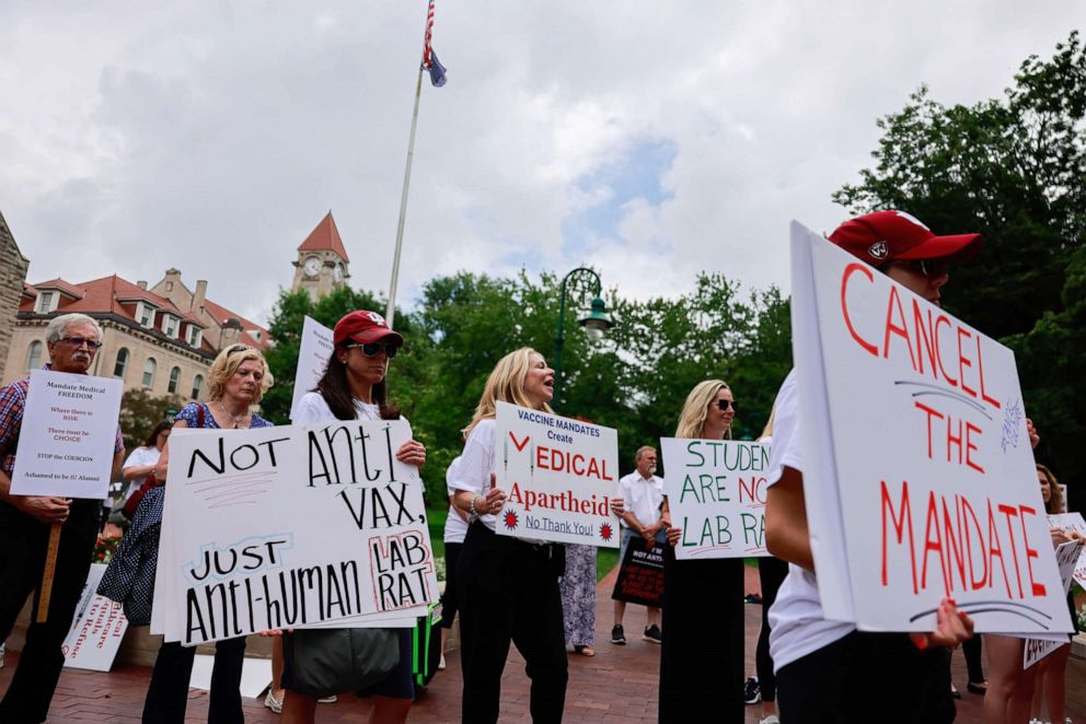 PHOTO: People with signs gather at Indiana University's Sample Gates to protest against mandatory COVID vaccinations that the school is requiring for students, staff and faculty during the upcoming fall semester, in Bloomington, Ind., June 10, 2021.