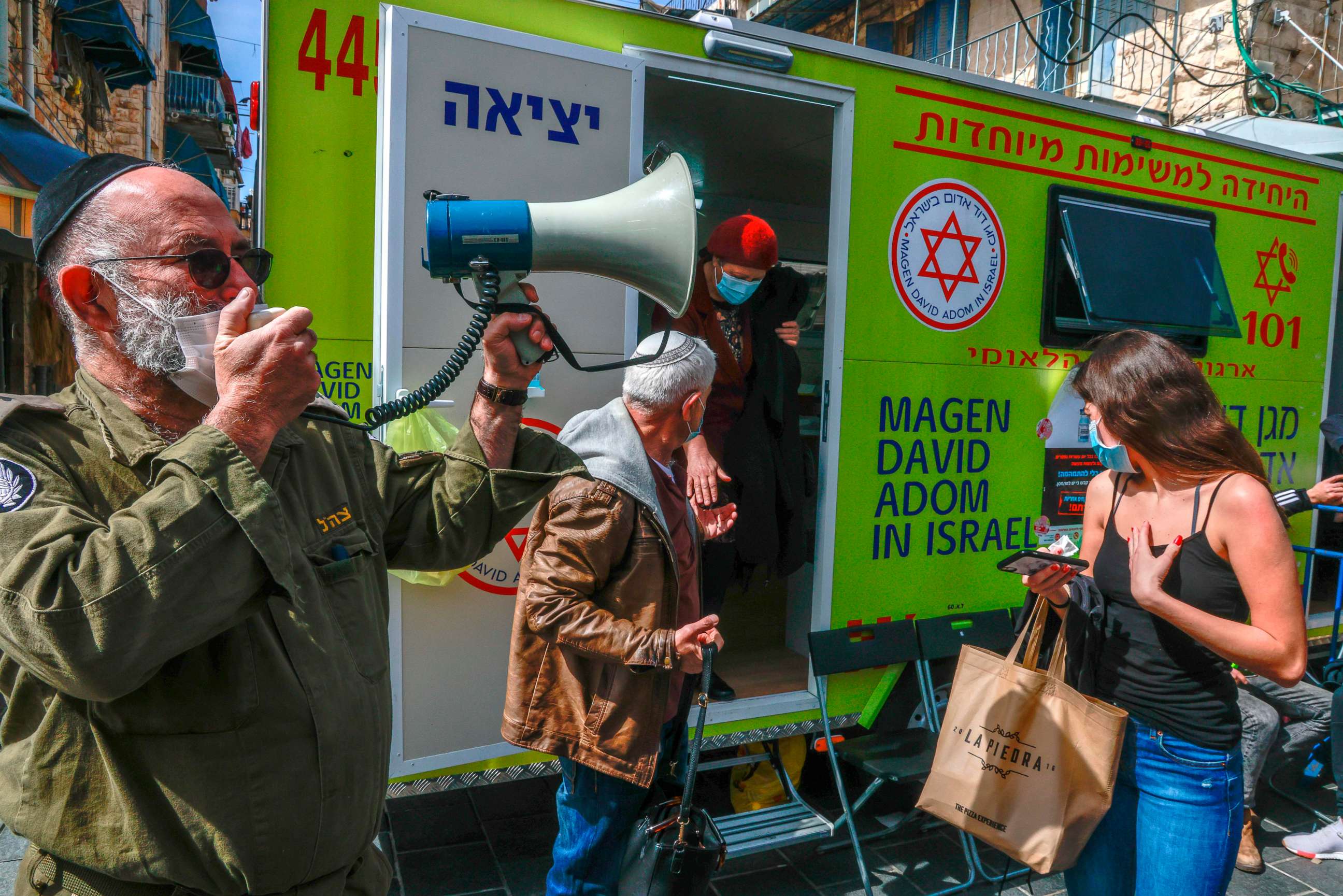 PHOTO: An officer of Israel's Home Front Command uses a megaphone to call patients during a coronavirus vaccination campaign at the Mahane Yehuda Market in Jerusalem on Feb. 22, 2021.