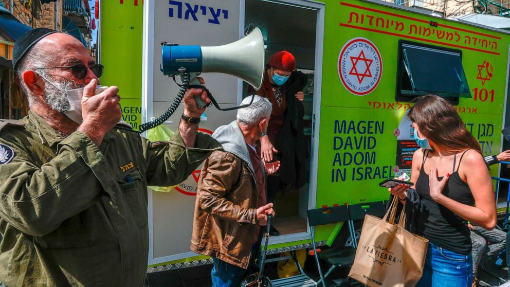PHOTO: An officer of Israel's Home Front Command uses a megaphone to call patients during a coronavirus vaccination campaign at the Mahane Yehuda Market in Jerusalem on Feb. 22, 2021.