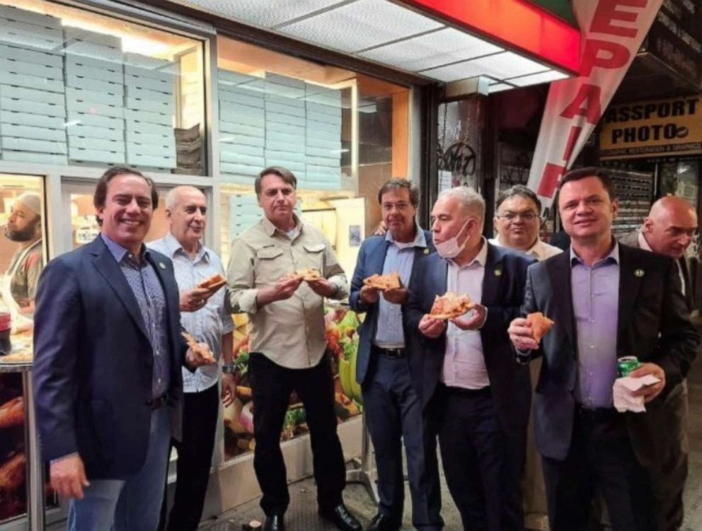 PHOTO:Brazil's President Jair Bolsonaro (3d L) eats pizza with Caixa Economica Federal Bank President Pedro Guimaraes, General Luiz Eduardo Ramos, Tourism Minister Gilson Machado Neto, Health Minister Marcelo Queiroga and others in N.Y, Sept. 19, 2021.