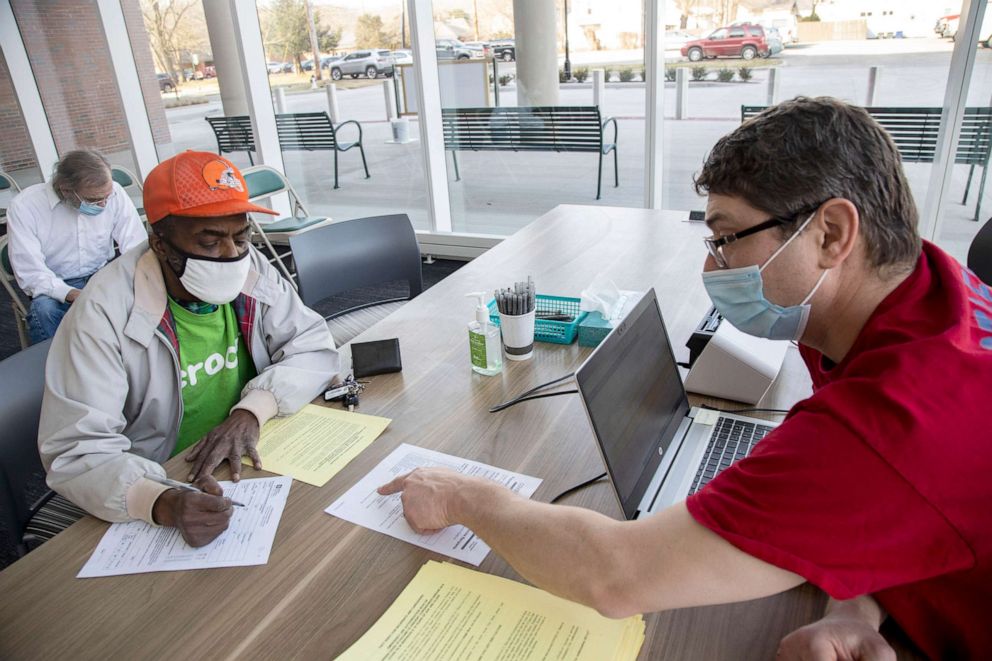 PHOTO: RA person receives instructions for filling out forms to receive the Johnson & Johnson vaccine in Athens, Ohio.