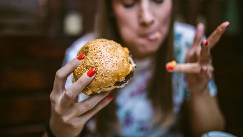 PHOTO: A young girl eats a cheeseburger in this stock photo.