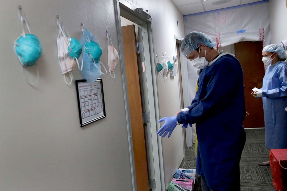 PHOTO: Dr. Drew Miller wears a homemade gown as he prepares to see potential COVID-19 patients May 20, 2020, in an outpatient clinic at Kearny County Hospital in Lakin, Kan. 