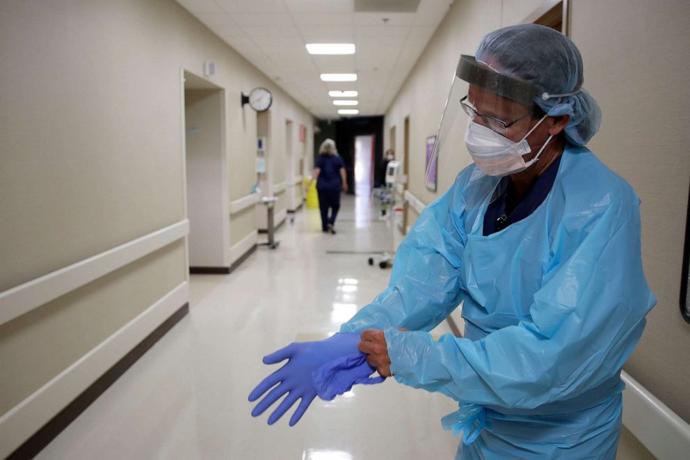 PHOTO: A registered nurse puts on protective gear as he prepares to check on a COVID-19 patient at Kearny County Hospital in Lakin, Kan., May 20, 2020.