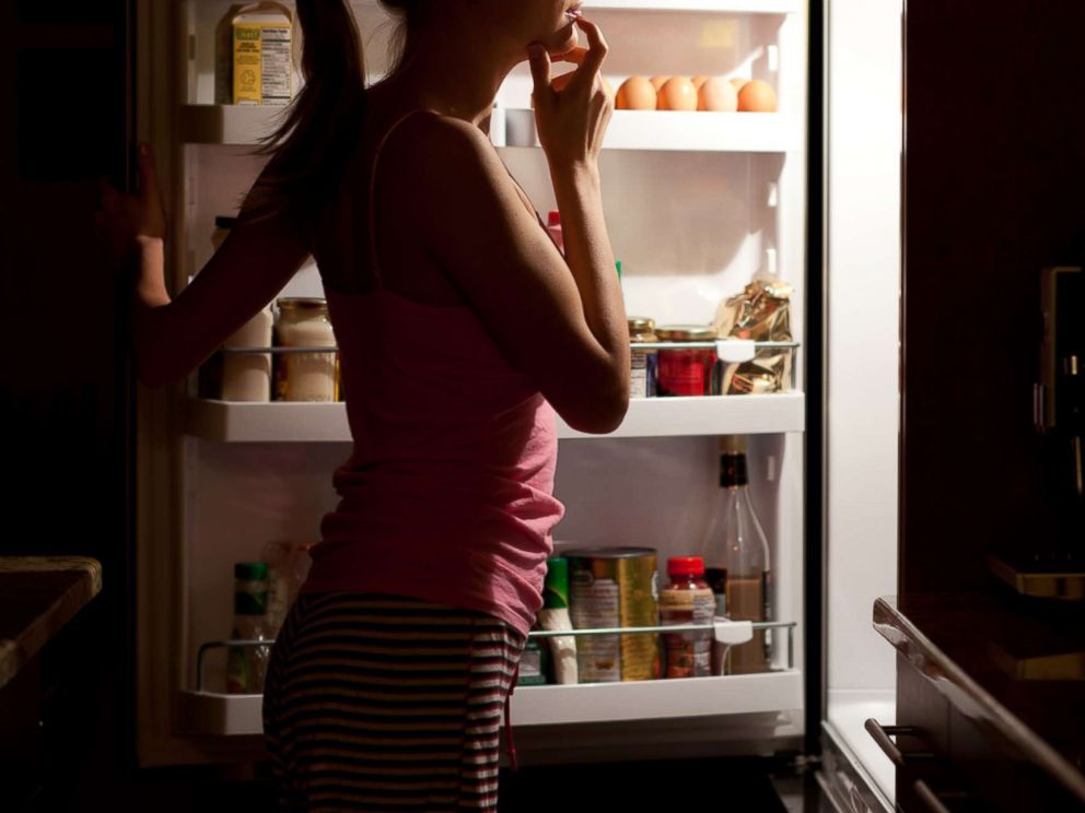 PHOTO: A woman is seen looking at food at night in this undated stock photo.