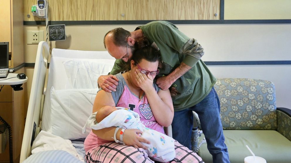 Crystal Matrau-Belt weeps while holding her newborn son, Jeremiah James Matrau-Skokan, at Bronson Methodist Hospital in Kalamazoo, Mich., Dec. 14, 2015. She is comforted by her uncle Michael Myers as she reacts to the deaths of her mother and fiance who were killed in a car crash on the way to the hospital.