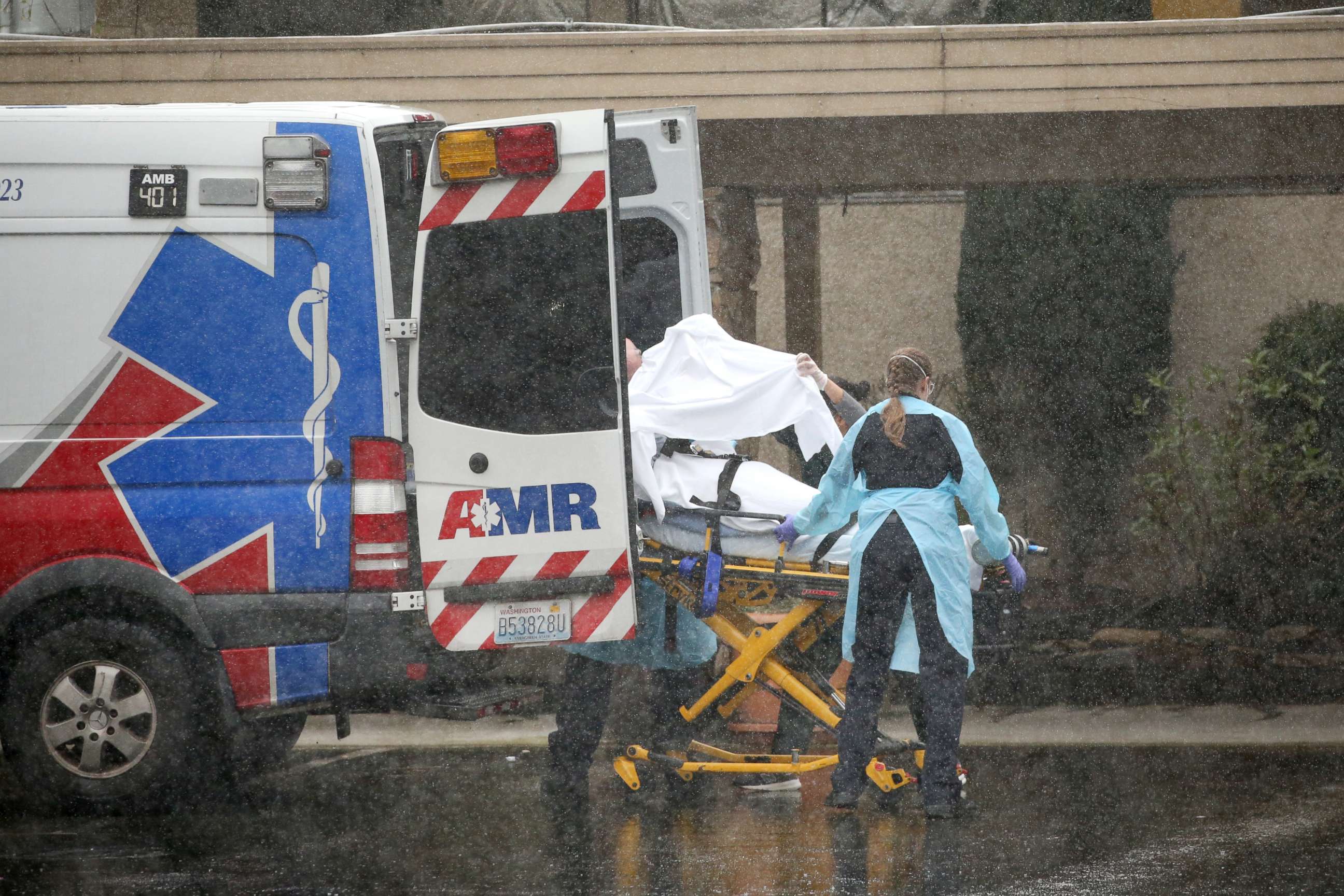 PHOTO: A patient is shielded as they are put into an ambulance during the pouring rain outside the Life Care Center of Kirkland on March 7, 2020 in Kirkland, Wash.