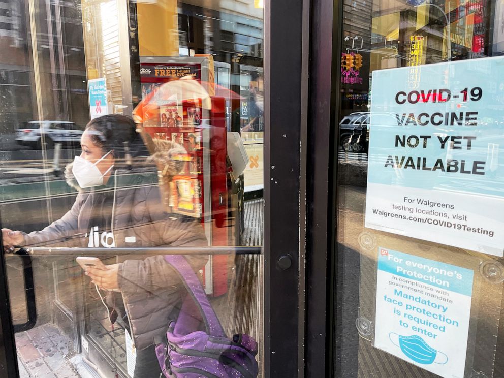 PHOTO: A woman walks out of a drugstore wearing a face mask in Times Square in New York City, Nov. 16, 2020.