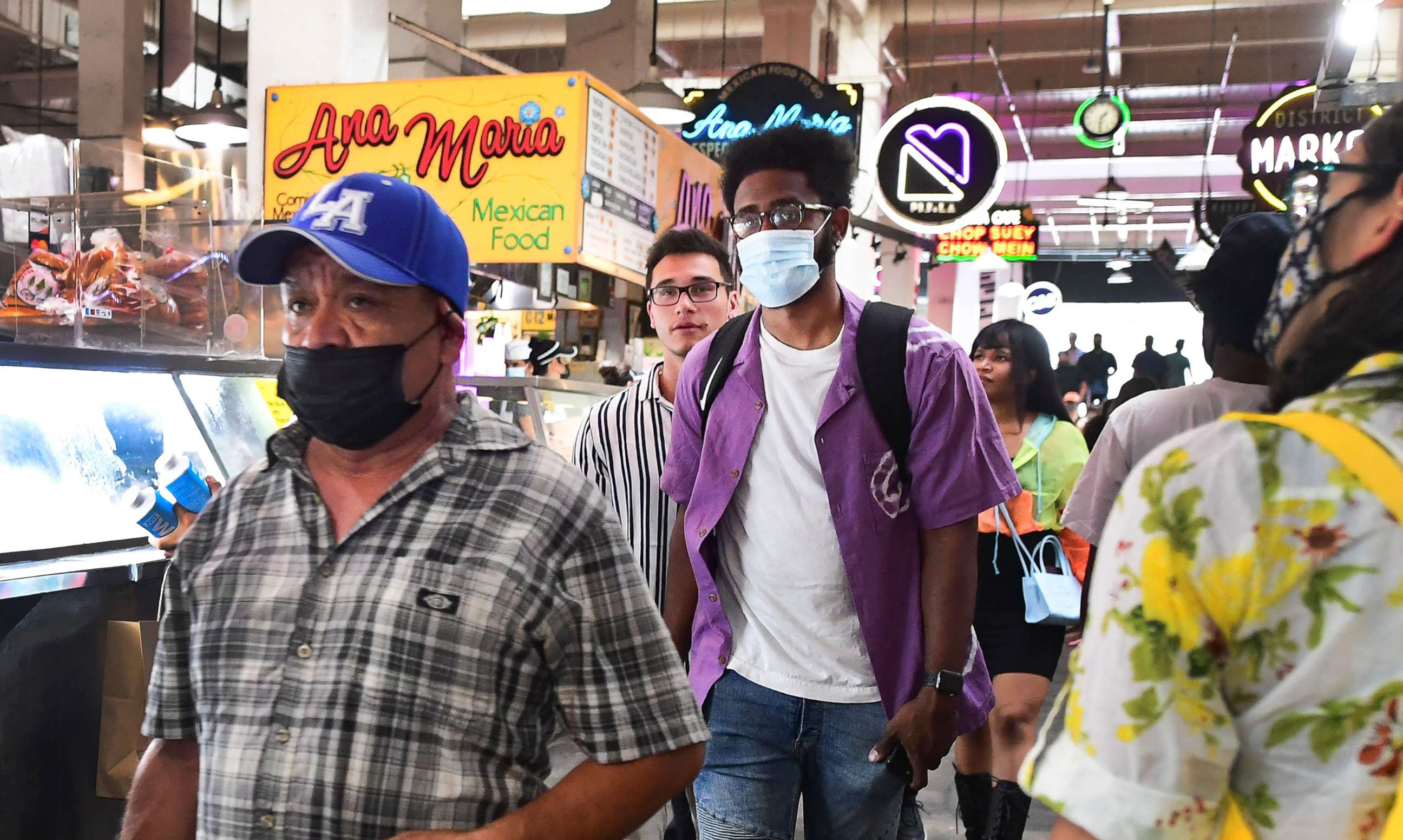 PHOTO: Masked and unmasked people make their way through Grand Central Market in Los Angeles, on June 29, 2021 as the WHO urges fully vaccinated people to continue wearing masks with the rapid spread of the delta variant.
