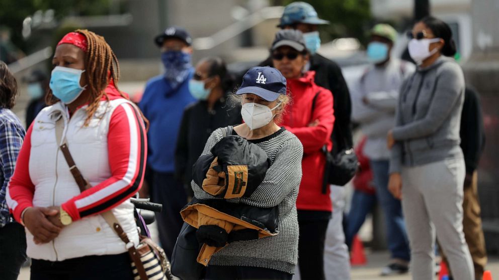 PHOTO: People receive protective masks and bandannas as they are handed out in Prospect Park as face coverings become mandatory in many establishments on May 3, 2020 in New York.
