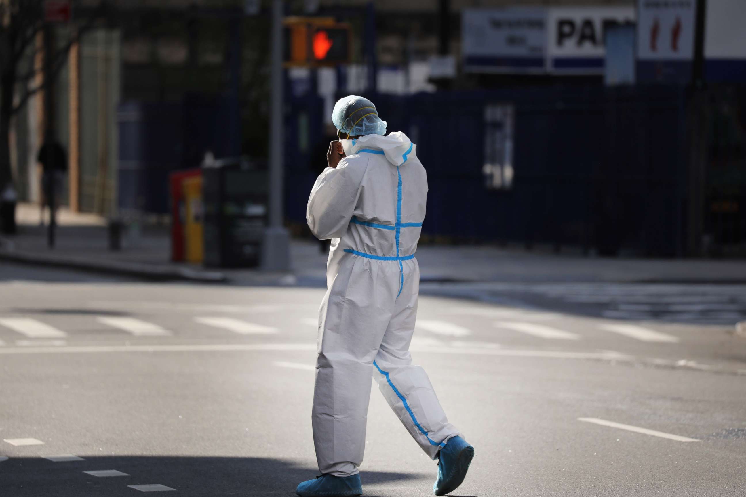 PHOTO: An employee of a nearby hospital with a special coronavirus intake area walks to a market in protective clothing, April 9, 2020, in Brooklyn, New York.