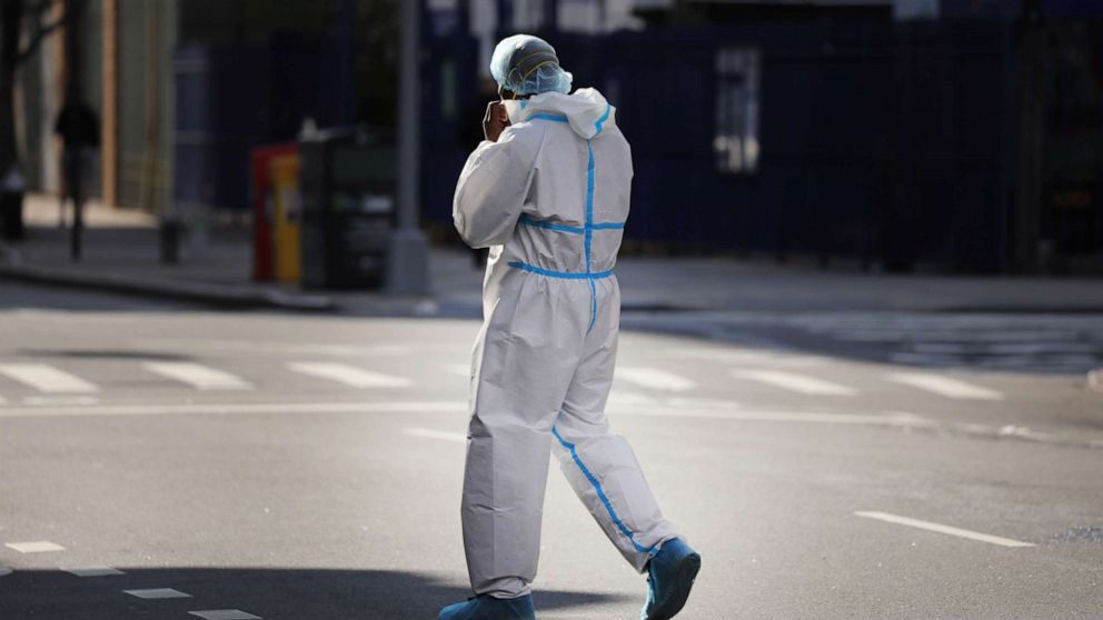 PHOTO: An employee of a nearby hospital with a special coronavirus intake area walks to a market in protective clothing, April 9, 2020, in Brooklyn, New York.
