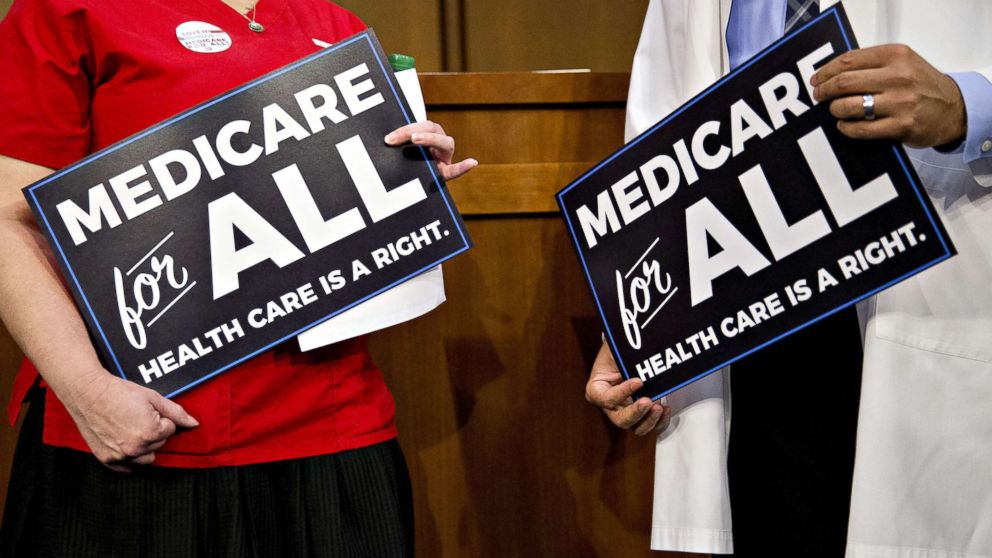 Attendees hold signs while waiting for a health care bill news conference to begin on Capitol Hill in Washington, Sept. 13, 2017.