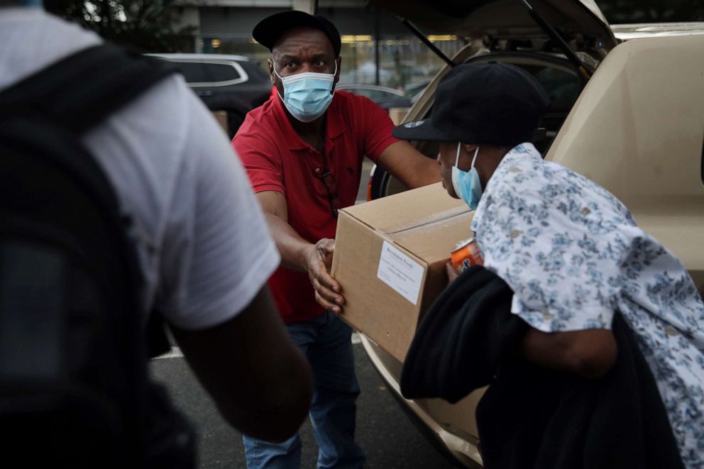 PHOTO: Guibert Tercino hands out boxes of food to people outside a comfort station run by the Boston Public Health Commission on Massachusetts Ave. in Boston, Sept. 10, 2020.
