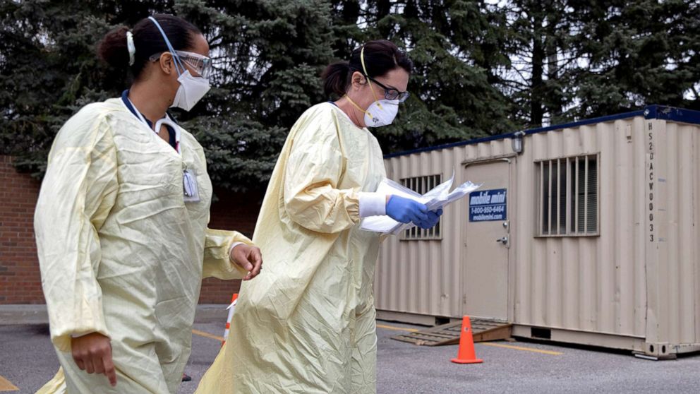 PHOTO: Emergency room nurses walk past a triage unit set up outside Beaumont Hospital to manage rising COVID-19 cases in Grosse Pointe, Mich., April 16, 2021. 