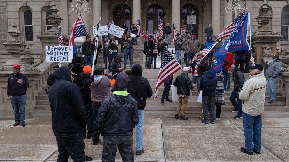 PHOTO: People hold flags and placards as hundreds of supporters of the Michigan Conservative Coalition protest against the state's extended stay-at-home order, April 15, 2020.